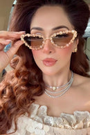 Woman wearing a stylish outfit with heart-shaped sunglasses and jewelry.