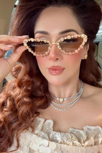 Woman wearing a stylish outfit with heart-shaped sunglasses and jewelry.